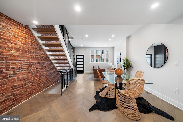 dining area featuring brick wall and light parquet flooring