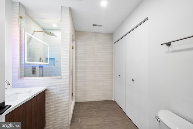 bathroom featuring toilet, vanity, and walk in shower