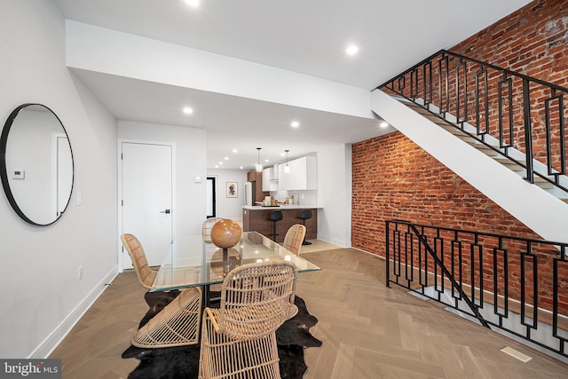 dining space with brick wall and light parquet floors