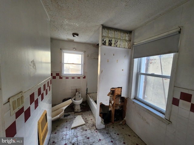 bathroom with a textured ceiling, a bidet, and heating unit