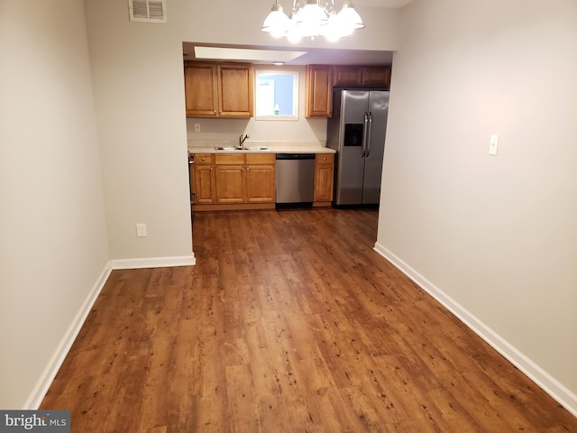 kitchen featuring sink, hanging light fixtures, stainless steel appliances, dark hardwood / wood-style flooring, and a notable chandelier