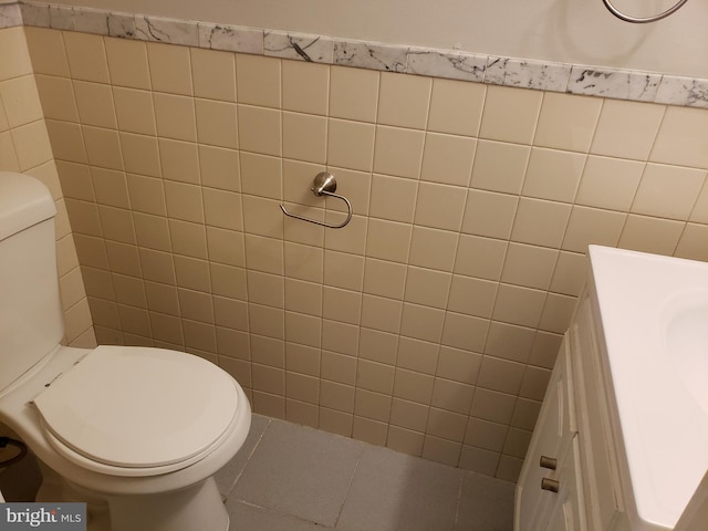 bathroom featuring tile patterned flooring, vanity, tile walls, and toilet