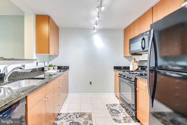 kitchen featuring rail lighting, sink, dark stone counters, light tile patterned floors, and black appliances