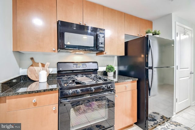 kitchen featuring black appliances, dark stone counters, and light tile patterned flooring