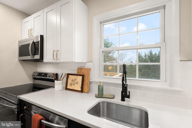 kitchen featuring a sink, white cabinets, light countertops, appliances with stainless steel finishes, and tasteful backsplash