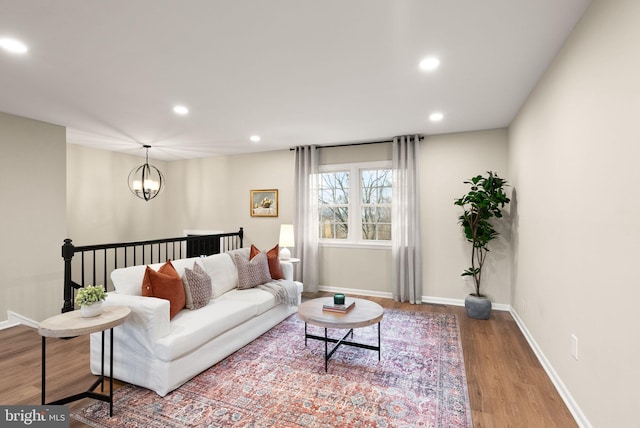 living room featuring recessed lighting, a notable chandelier, baseboards, and wood finished floors