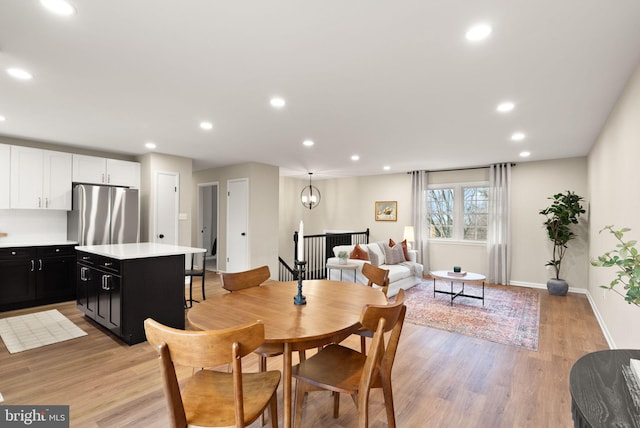 dining area with baseboards, light wood-type flooring, a notable chandelier, and recessed lighting