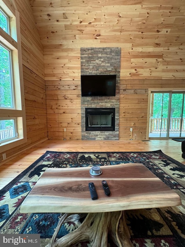 unfurnished living room with a stone fireplace, wood walls, and plenty of natural light