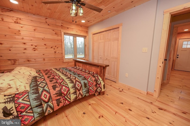 bedroom with wood walls, wooden ceiling, ceiling fan, light hardwood / wood-style floors, and a closet