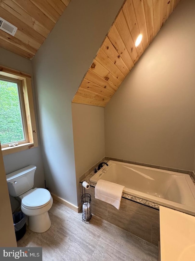 bathroom with toilet, lofted ceiling, tiled tub, and wooden ceiling