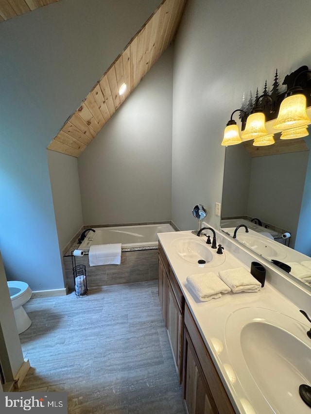 bathroom featuring vanity, toilet, a washtub, and vaulted ceiling