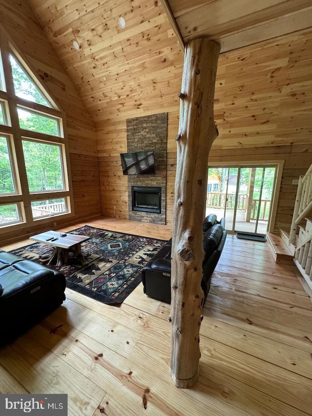 unfurnished living room featuring light wood-type flooring, a stone fireplace, wood walls, and wood ceiling