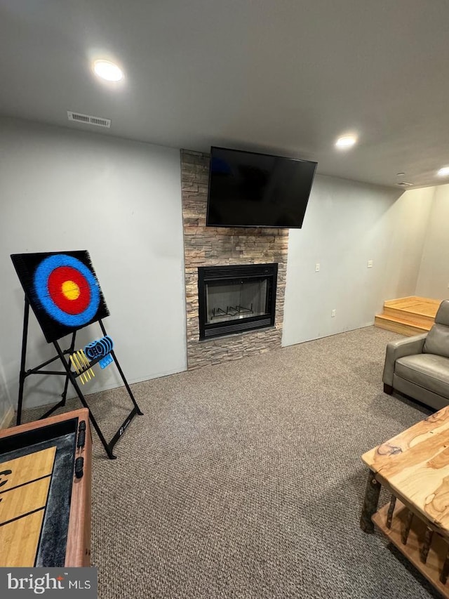 carpeted living room with a stone fireplace