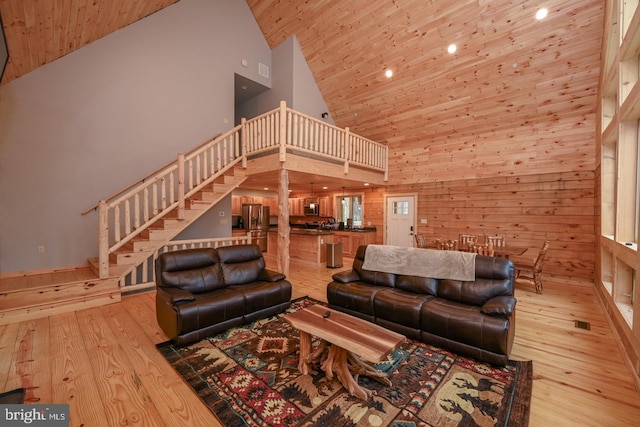 living room featuring wood walls, light hardwood / wood-style floors, wooden ceiling, and high vaulted ceiling