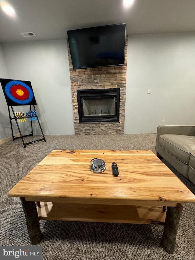 carpeted living room with a stone fireplace