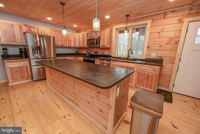 kitchen with stainless steel appliances, sink, decorative light fixtures, a center island, and light hardwood / wood-style floors