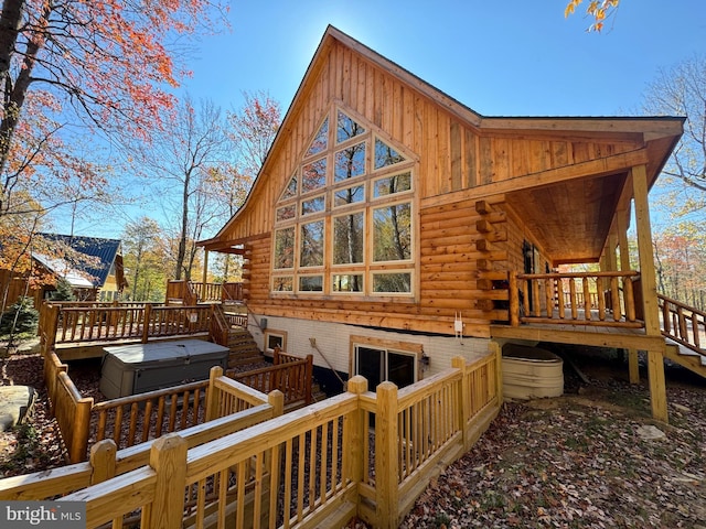 back of house with a covered hot tub