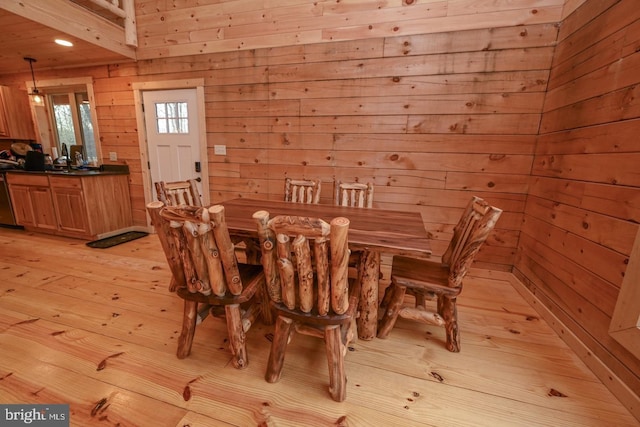 dining space with wood walls and light hardwood / wood-style floors