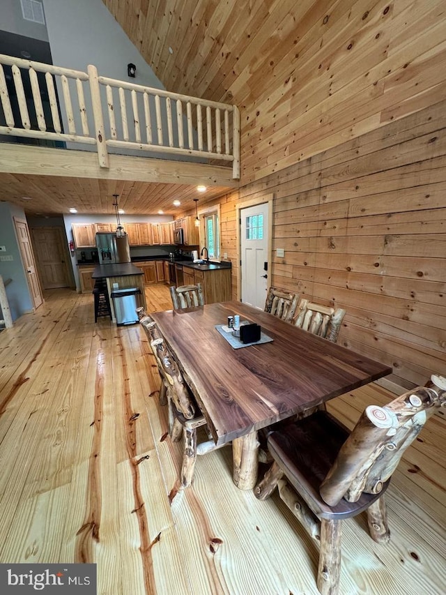 dining area with wood ceiling, wooden walls, high vaulted ceiling, and light hardwood / wood-style floors