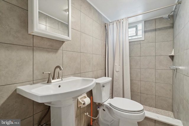 bathroom with a shower with curtain, toilet, tile walls, and sink