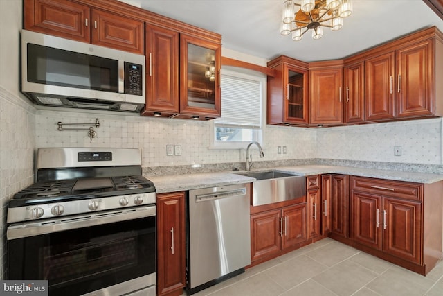 kitchen featuring a chandelier, appliances with stainless steel finishes, light stone counters, and sink