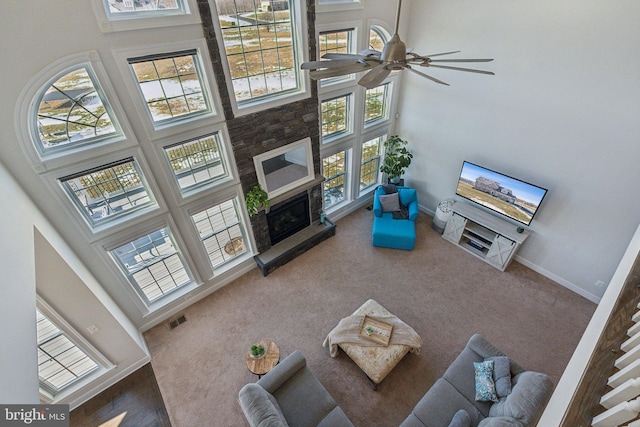 living room with a high ceiling, a healthy amount of sunlight, a large fireplace, and ceiling fan