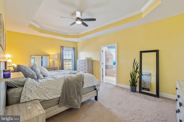 bedroom featuring ensuite bath, ornamental molding, a raised ceiling, and ceiling fan