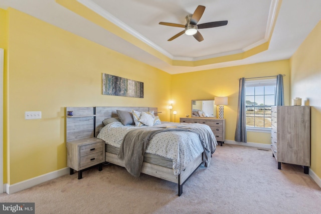 carpeted bedroom with crown molding, ceiling fan, and a raised ceiling