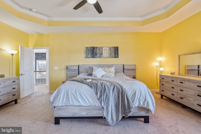 carpeted bedroom with ornamental molding, ceiling fan, and a tray ceiling