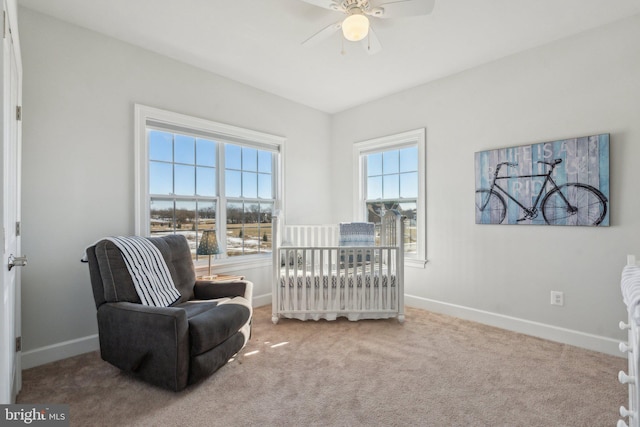 carpeted bedroom with ceiling fan and a crib