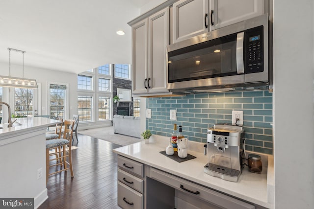 kitchen with sink, gray cabinetry, hanging light fixtures, backsplash, and dark hardwood / wood-style flooring