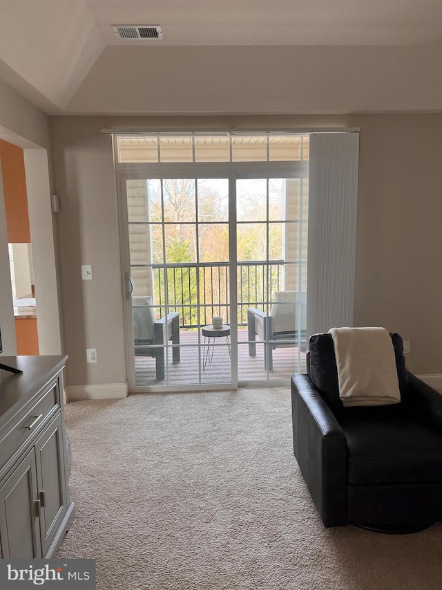 living area featuring light carpet, vaulted ceiling, and plenty of natural light