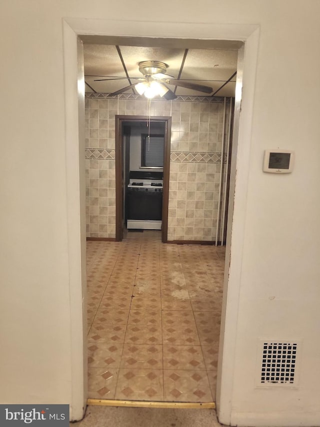 corridor featuring tile patterned floors and tile walls