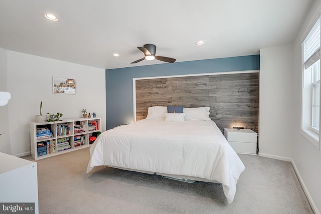 bedroom with light colored carpet, ceiling fan, and wooden walls