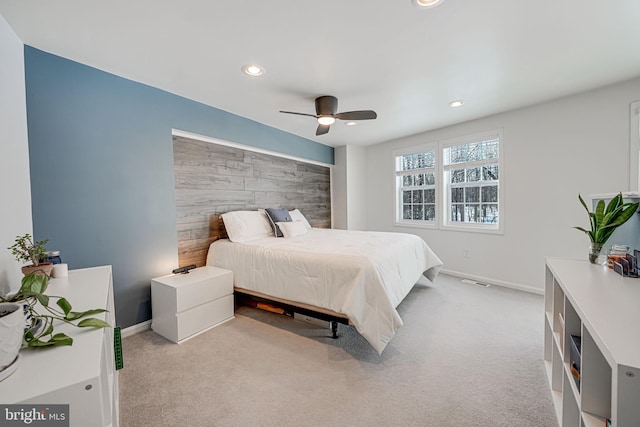 carpeted bedroom with ceiling fan and wood walls