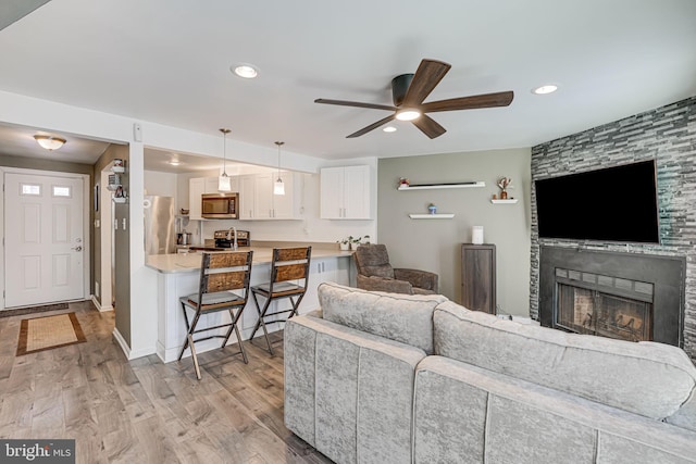 living room with ceiling fan, a fireplace, and light hardwood / wood-style flooring