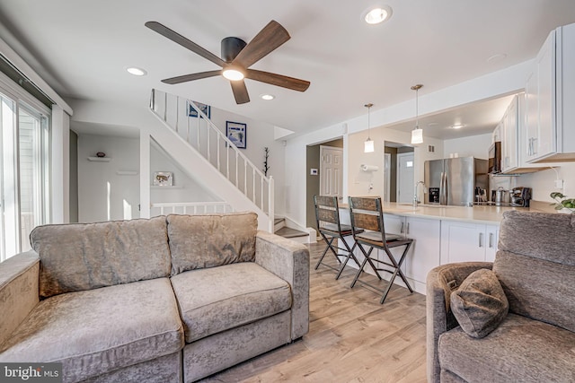 living room featuring ceiling fan, sink, and light hardwood / wood-style floors