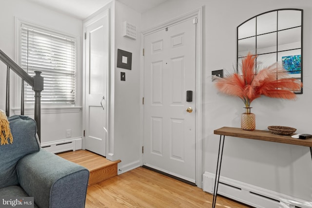 foyer entrance with wood-type flooring, a baseboard heating unit, and plenty of natural light