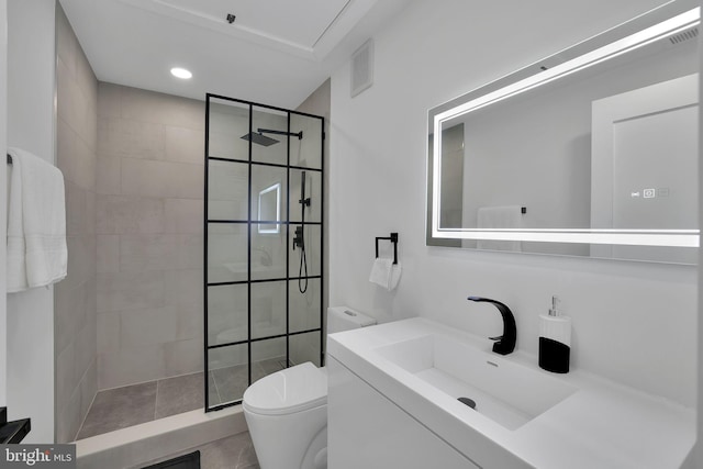 bathroom with vanity, toilet, and a tile shower