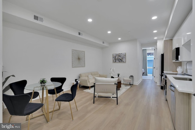 living room featuring sink and light hardwood / wood-style floors