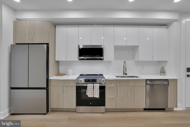 kitchen featuring white cabinetry, sink, light hardwood / wood-style floors, stainless steel appliances, and light brown cabinets