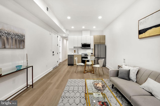 living room with light hardwood / wood-style floors and sink