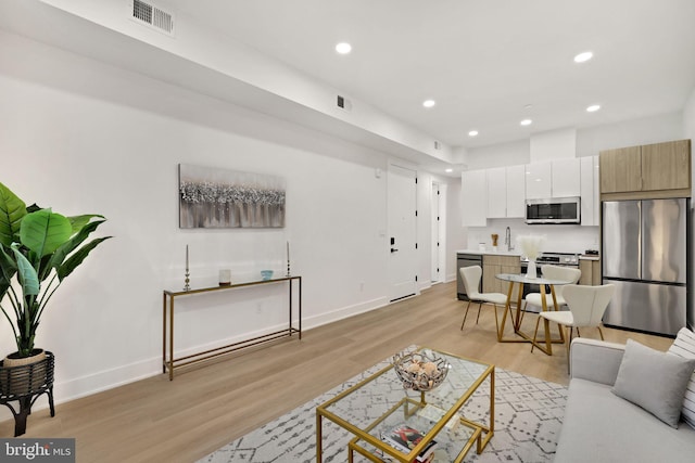 living room with sink and light hardwood / wood-style flooring