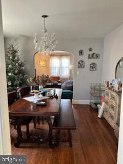 dining space with dark hardwood / wood-style flooring and an inviting chandelier