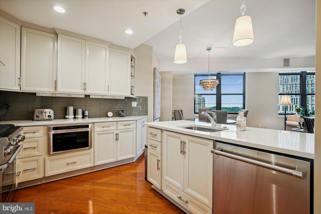 kitchen featuring sink, stainless steel appliances, a notable chandelier, pendant lighting, and decorative backsplash