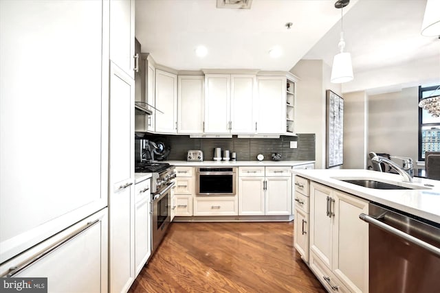 kitchen featuring appliances with stainless steel finishes, backsplash, dark wood-type flooring, sink, and pendant lighting