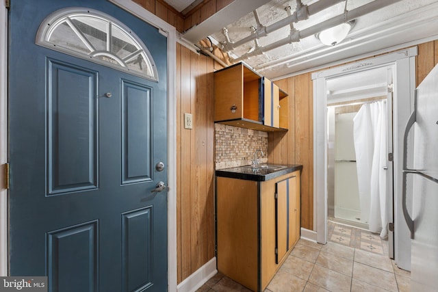 kitchen with wood walls, sink, light tile patterned floors, tasteful backsplash, and white fridge