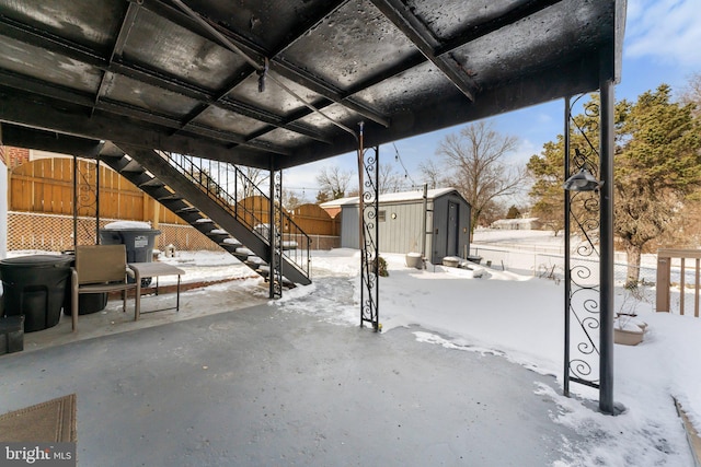 snow covered patio featuring a storage unit