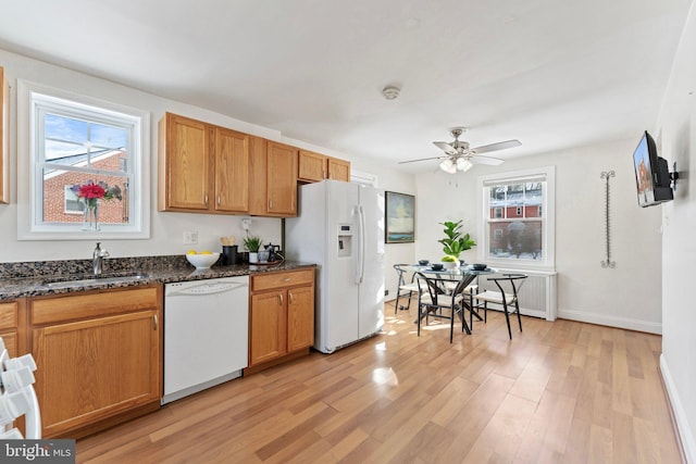 kitchen with ceiling fan, sink, dark stone countertops, light hardwood / wood-style floors, and white appliances