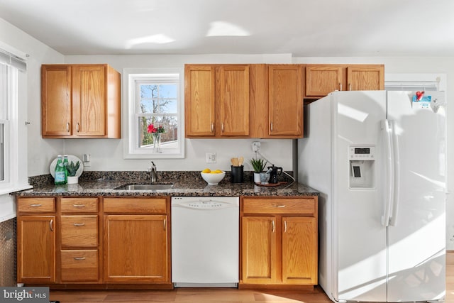 kitchen with a healthy amount of sunlight, white appliances, dark stone counters, and sink